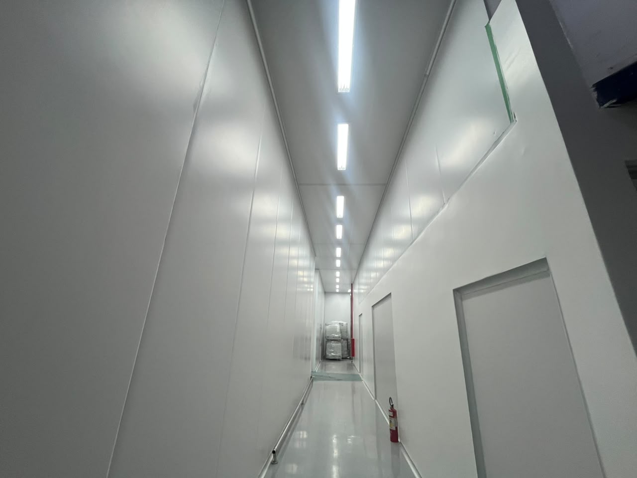 Corredor de sala limpa com painéis isotérmicos e piso epóxi instalado pela IsoClean Brasil